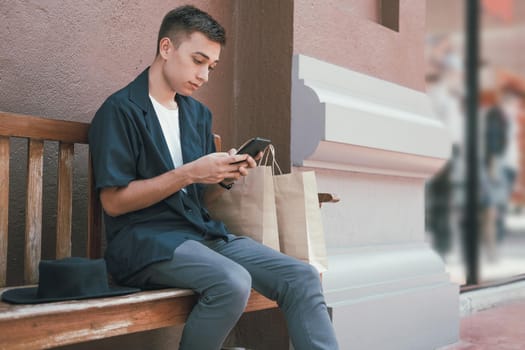 man using mobile smart phone with paper shopping bags. consumerism lifestyle