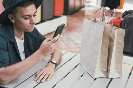 man using mobile smart phone with paper shopping bags. consumerism lifestyle