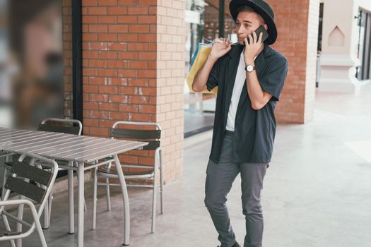 man holding paper shopping bags & talking on mobile smart phone. consumerism lifestyle