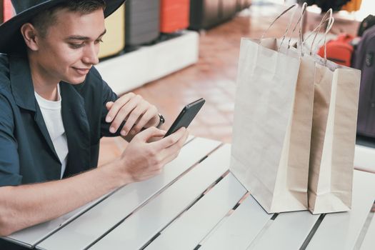 man using mobile smart phone with paper shopping bags. consumerism lifestyle