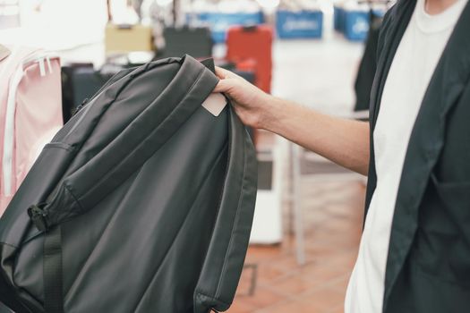 man holding shopping bags choosing backpack at store shop mall