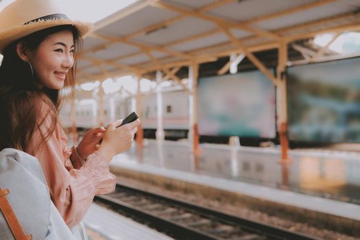 woman traveler with backpack use app on mobile smart phone at train station. trip journey travel concept