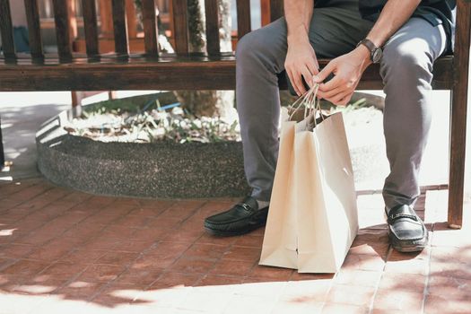 man sitting resting with shopping bags at shopping mall. consumerism lifestyle