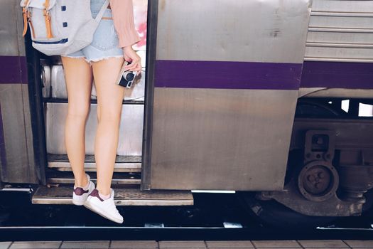 young woman tourist traveler stepping up to train on railway at train station. Travel journey trip concept