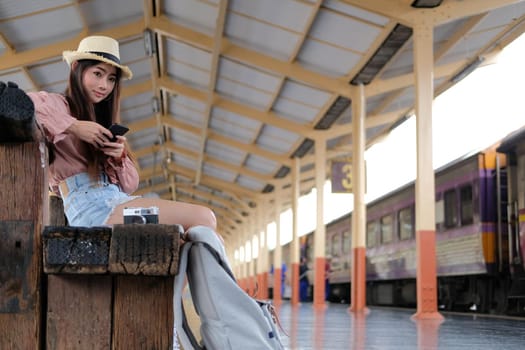 young woman traveler using mobile smart phone at train station. Travel journey trip concept