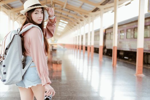 young asian woman  backpacker traveler with camera backpack at train station. journey trip travel concept