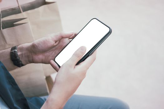 man using mobile smart phone with paper shopping bags. consumerism lifestyle