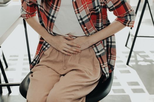 girl woman touching stomach with hurt pain suffering from stomachache menstrual period cramp at workplace