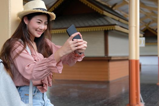 asian woman use smart phone to take selfie photo at train station. traveler travel on holiday