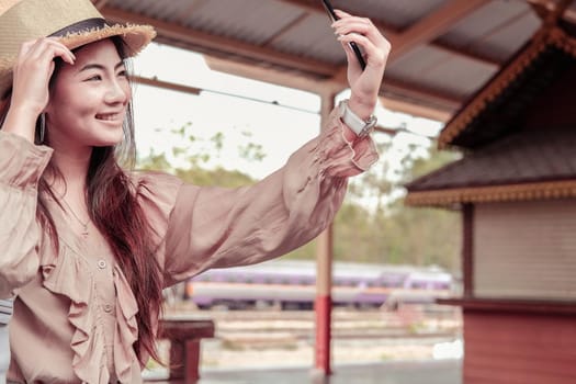 asian woman use smart phone to take selfie photo at train station. traveler travel on holiday