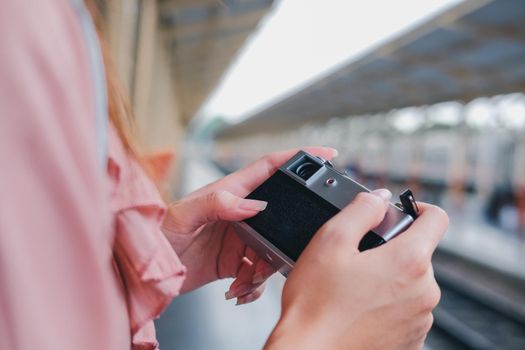 woman traveler holding camera taking photo at train station. travel trip journey concept