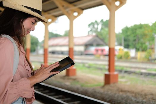 young woman traveler using tablet at train station. Travel journey trip concept