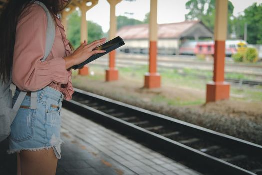 young woman traveler using tablet at train station. Travel journey trip concept