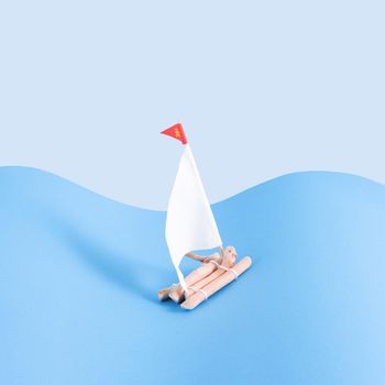 Wooden raft with a sails on a light and dark blue background. Minimal concept. Square with copy space