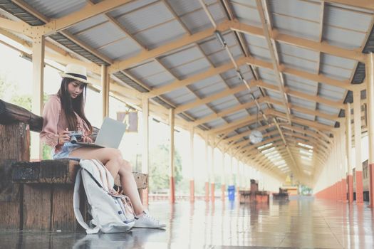 young woman traveler using computer at train station. Travel journey trip concept