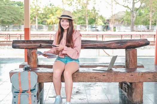 young woman traveler with mobile smart phone & map at train station. Travel journey trip concept