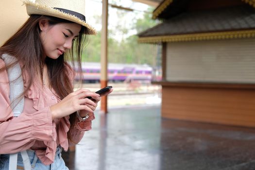 woman traveler with backpack use app on mobile smart phone at train station. trip journey travel concept