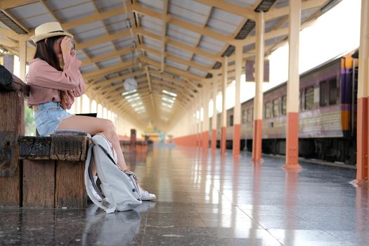 woman traveler holding camera taking photo at train station. travel trip journey concept