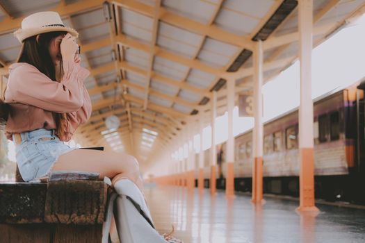 woman traveler holding camera taking photo at train station. travel trip journey concept