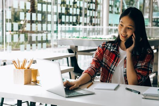 woman girl teenager freelancer talking on phone working on computer at workplace