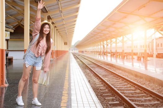 woman traveler with backpack map raising waving hand at train station. trip journey travel concept