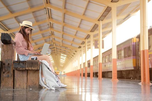young woman traveler using computer at train station. Travel journey trip concept