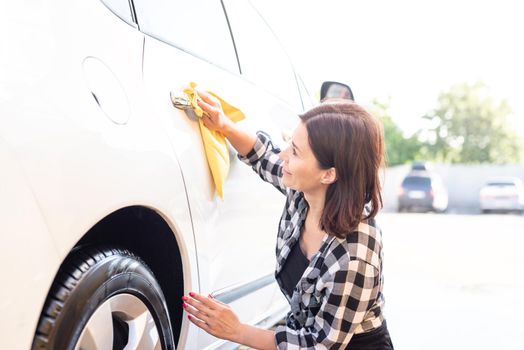 Woman wiping car door handle with rag during car wash