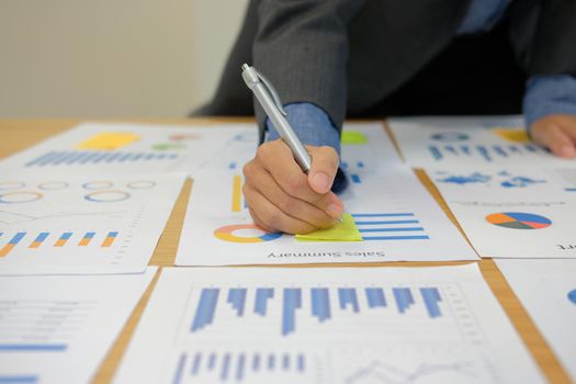 Businessman writing on sticky note on business document at workplace. paper reminder schedule for discussing creativity idea at office.
