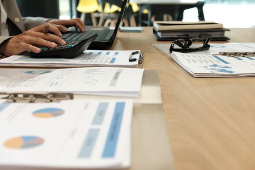 financial adviser working with calculator, business document & computer at office. accountant doing accounting & calculating revenue & budget. bookkeeper making calculation. finance & economy concept
