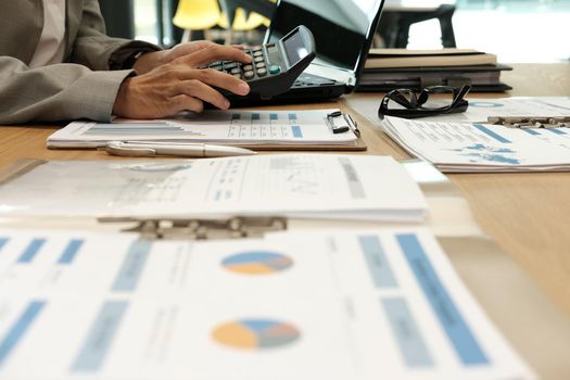 financial adviser working with calculator, business document at office. accountant doing accounting & calculating revenue & budget. bookkeeper making calculation. finance & economy concept
