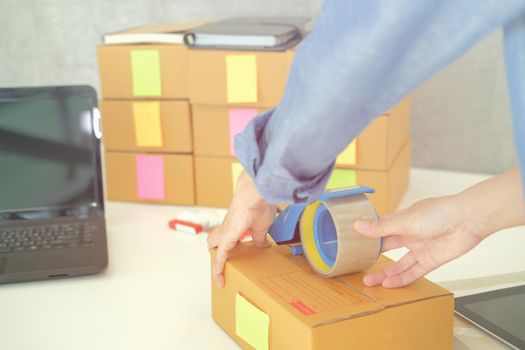 startup small business owner packing cardboard box at workplace. freelance woman entrepreneur seller prepare parcel box of product for deliver to customer.  Online selling, e-commerce concept