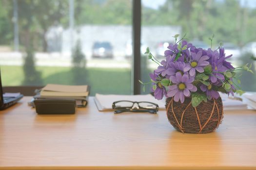 purple artificial flower notebook document eyeglasses on office desk