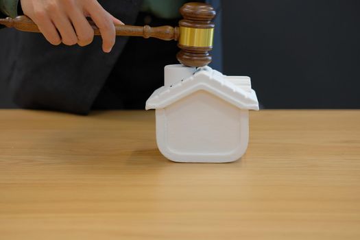 lawyer with judge gavel knocking house model at courtroom. real estate dispute & property auction concept