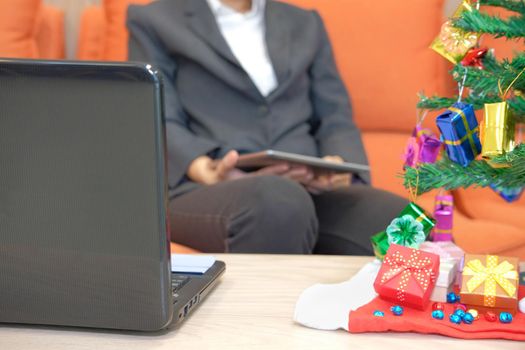 man sitting on sofa using tablet. businesswoman texting message on touchpad during xmas. christmas holiday new year celebration season greetings