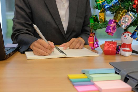 man writing reminder schedule note on notebook. businessman working organizing plan at workplace office during christmas new year holiday