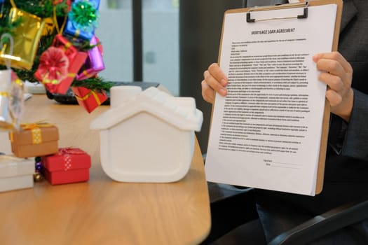 realtor man show mortgage loan agreement to client.  real estate agent house developer present contract document to customer. sale and purchase property with house model during christmas holiday