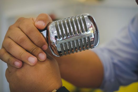 singer hand holding silver chrome metal vintage microphone