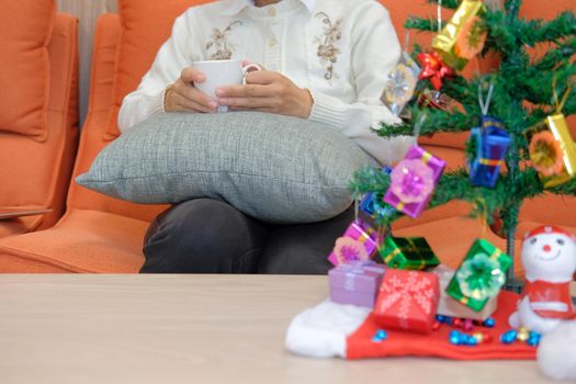 woman wearing cream cardigan holding coffee cup with gift box christmas tee. xmas new year celebration