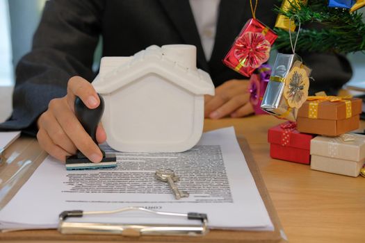 real estate agent with house key using stamper for stamping approved on mortgage loan contract agreement document during christmas