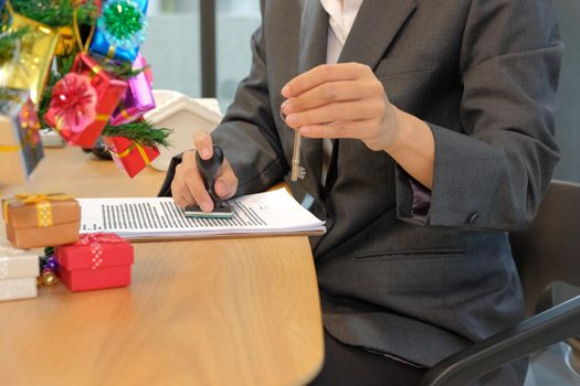 real estate agent with house key using stamper for stamping approved on mortgage loan contract agreement document during christmas