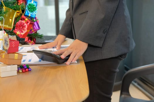 financial adviser working with calculator at office. accountant doing accounting & calculating revenue & budget. bookkeeper making calculation during christmas new year holiday