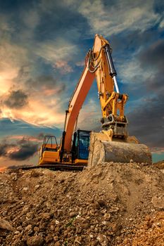 Crawler excavator during earthmoving works on construction site at sunset