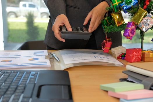 financial adviser working with calculator at office. accountant doing accounting & calculating revenue & budget. bookkeeper making calculation during christmas new year holiday