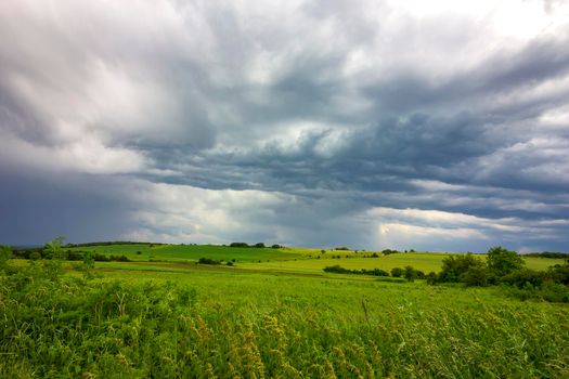 scenic view of stormy clouds over the green field