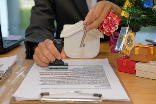 real estate agent with house key using stamper for stamping approved on mortgage loan contract agreement document during christmas