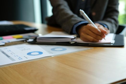 man writing reminder schedule note on notebook. businessman working organizing plan at workplace coworking office