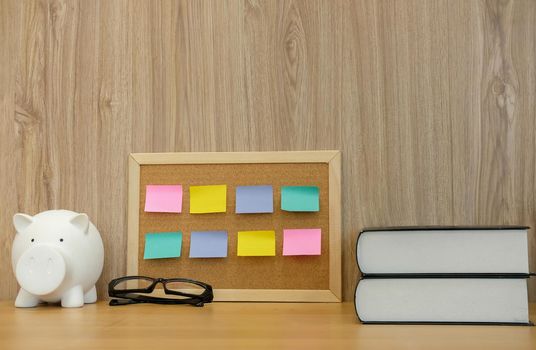 sticky notes paper reminder on cork board & piggy bank. money saving finance investment concept