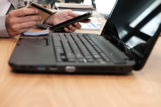 man holding credit card using smart phone for online shopping. businessman purchase product from internet, make payment on bank website at workplace