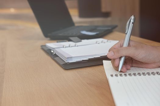 man writing reminder schedule note on notebook. businessman working organizing plan at workplace coworking office