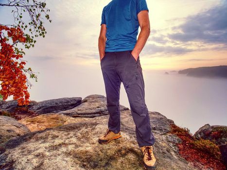 Gloomy nostalgic view into fall nature with lonely melancholic adult man. Sportsman without  jacket standing on the top  in misty morning and thinking 